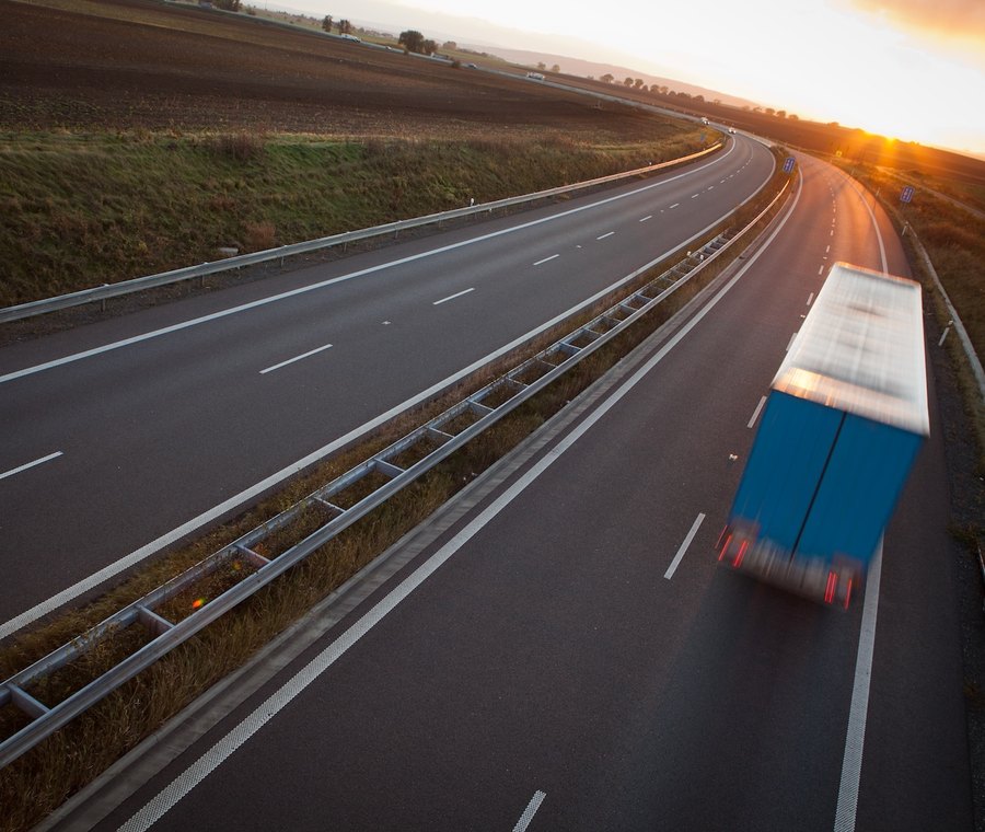 Freight truck speeding along a highway at sunset, motion blurred