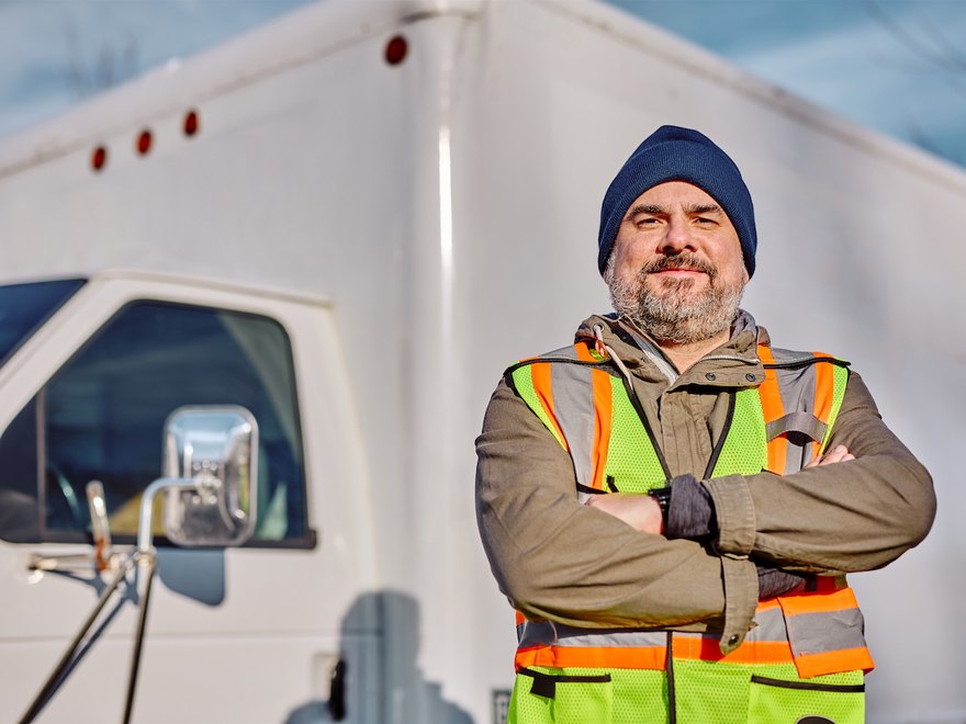 Box truck driver in a safety vest standing in front of his truck